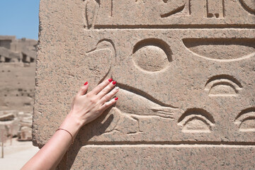 A woman hand touching an Egyptian hieroglyph 