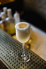 Glass of gin sour cocktail decorating with circles of honeycomb beeswax. 