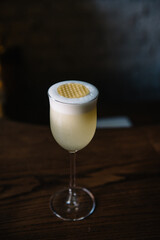 Glass of gin sour cocktail decorating with circles of honeycomb beeswax. 