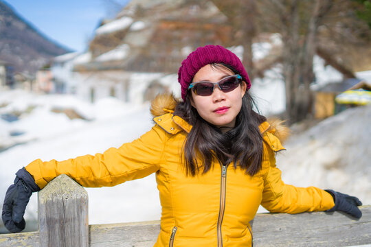 winter lifestyle portrait of young happy and attractive Asian Korean woman at beautiful snow mountains landscape enjoying Easter holidays in Swiss Alps smiling cool