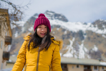 winter lifestyle portrait of young happy and attractive Asian Japanese woman at beautiful snow mountains landscape enjoying Easter holidays in Swiss Alps