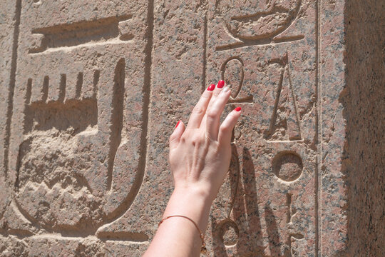 A woman hand touching an Egyptian hieroglyph 
