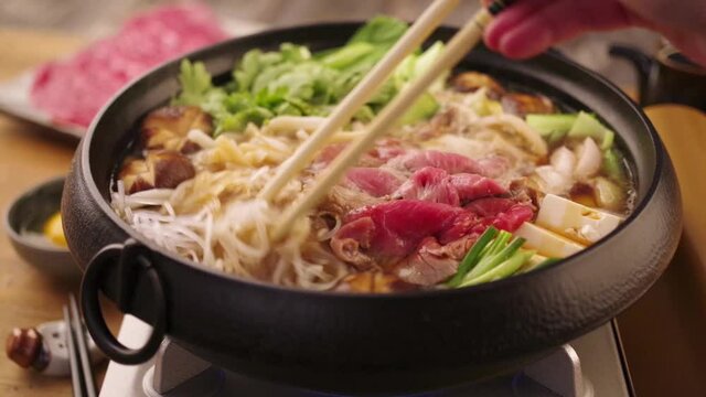 Traditional Japanese sukiyaki is boiling in a cast iron pot