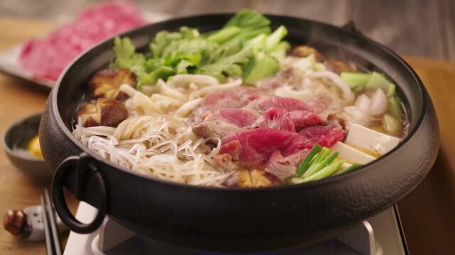 Traditional Japanese sukiyaki is boiling in the cast iron pot