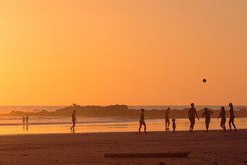 Group of friends and family playing and having fun at sunset on the beach