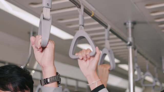 Close up hand of business people hold strap or handrail firmly on the sky train or subway their way to working transportation people diversity lifestyle concept.