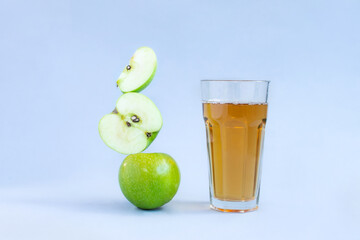 Apple juice levitation. Balance food levitate conceptual creative still life. Balance of fresh green apple slices and a glass of apple juice on a blue background. Levitation food balance symbol