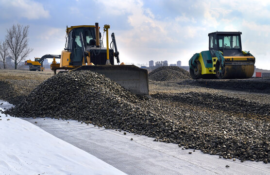 Carrying out construction works for laying the road. The work of a yellow bulldozer leveling gravel for subsequent asphalt paving