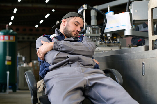 Tired Factory Worker Sleeps At Workplace Near Production Line Breaking Rules