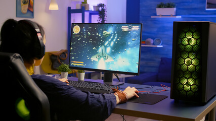 Gamer playing space shooter video game on powerful computer using RGB gaming equipment. Pro player...