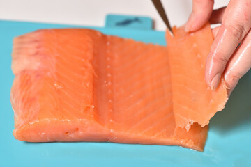 Chef cuts red fish into thin slices on a cutting board