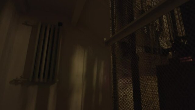 A vintage elevator is descending in a dark old building. Stock footage. View inside of a house entrance of an elevator with iron grating.