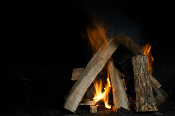Fire in the hearth - fire, wood and smoke on a dark background