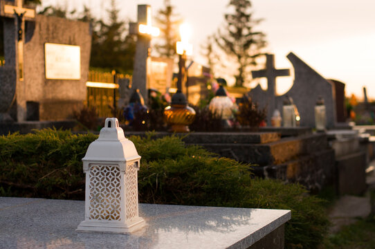 A tomb decorated with candles and flowers with cementary in the background.
