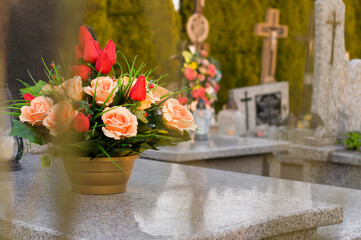 A tomb decorated with candles and flowers with cementary in the background.