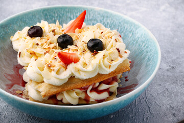 Slice cake of puff pastry with strawberry and blueberry on plate closeup