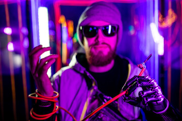 handsome young man with metal bionics prosthetic arm wrapped on wire in neon background space