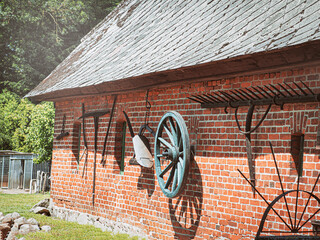 Obraz premium Countryside house wall with rural tools and wheels in sunny summer day.