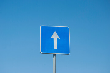 Blue rectangle one way road traffic sign closeup on blue sky background