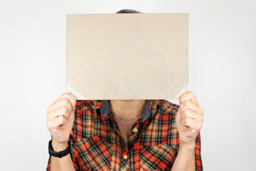 Woman on a light background holds a cardboard sheet without inscriptions, place for text, blank for advertising. Mockup