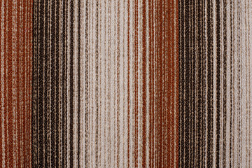 Fabric background with a pronounced texture and vertical lines of different colors from beige to dark brown