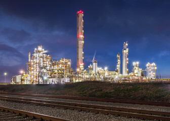 Night scene with illuminated petrochemical production plant with train tracks on the foreground, Antwerp, Belgium.