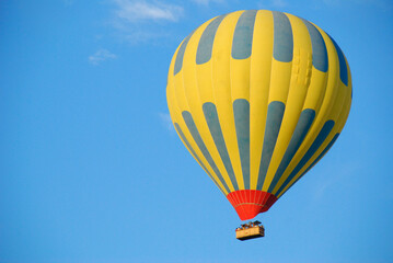 Yellow hot air balloon flying in the blue sky of Cappadocia.