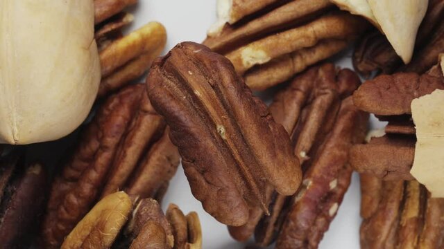 Peeled pecans spin against the background of other nuts. Close-up. View from above.