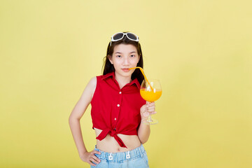 Woman drinking juice in summer on yellow background