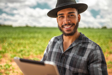 Latin American Farmer working on soybean plantation, examining crop development on tablet