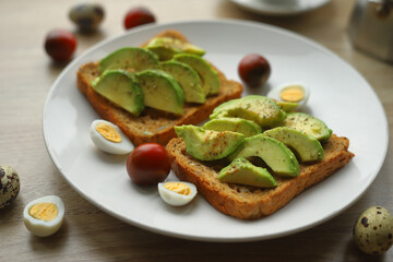 Toast with sliced avocado quail eggs cherry tomatoes close-up. Healthy breakfast.