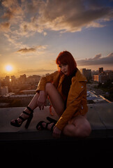 Girl on the roof of a building against the backdrop of a sunset in the city