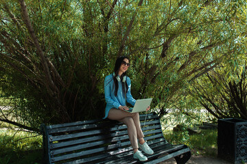 Concept people at work. A young brunette girl working in park on bench. 