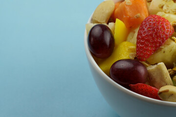 Fruit salad with chestnuts and granola in a bowl. Multicolored ripe fruits. Pineapple, mango, grape, strawberry, papaya, melon, banana and kiwi..