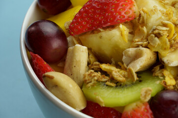 Fruit salad with chestnuts and granola in a bowl. Multicolored ripe fruits. Pineapple, mango, grape, strawberry, papaya, melon, banana and kiwi..