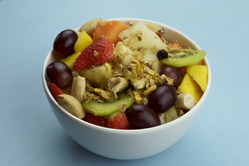 Fruit salad with chestnuts and granola in a bowl. Multicolored ripe fruits. Pineapple, mango, grape, strawberry, papaya, melon, banana and kiwi..