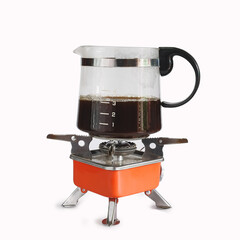 Coffee jar glass on top of camping stove on background.