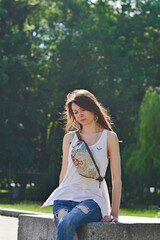 Pretty brunette sits on a park bench. Sunset.
