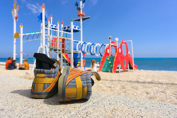 Shoes and socks of a child laying on the ground next to a playground at the beach in Altea, Spain