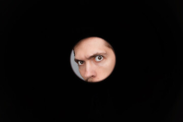 Man's eyes looking in black hole. Empty place for a text or object. Close-up shot of shocked young...
