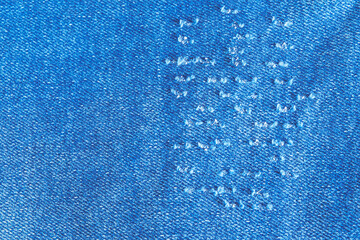 Tear of denim texture with a hole and threads showing.