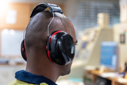Male worker with hearing protectors, working in the engine control room of container ship.