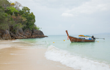 Fototapeta na wymiar Beautiful scenic view lontail wooden boat on the beach with sea wave in the island in Thailand shows relaxing atmosphere for summer vacation under blue and clear sky which is the paradise for tourism.
