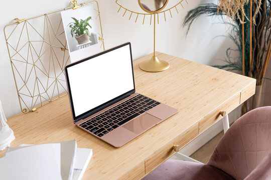 Laptop With Blank White Screen On The Desk, Mock Up. Personal Laptop Computer On Wood Table In Living Room With Modern Interior.