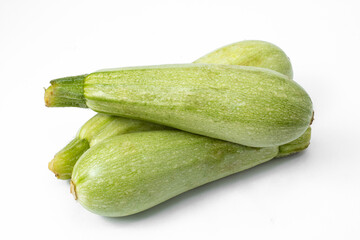 Group with three fresh, raw and whole Italian zucchinis, stacked on white background