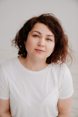 smiling brunette woman with curly hair in a T-shirt on a white background 