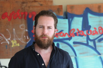 handsome man with beard in urban setting with graffiti background and dark navy shirt 