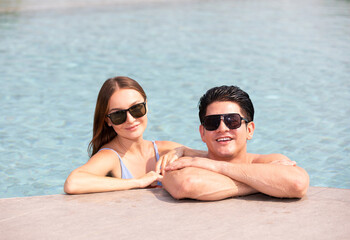 Fototapeta premium portrait couple wearing sunglasses, and enjoy each other in swimming pool