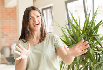 pretty woman feeling terrified, backing off and screaming in horror and panic, reacting to a...