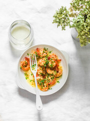 Garlic butter fried shrimp and a glass of white wine on a light background, top view